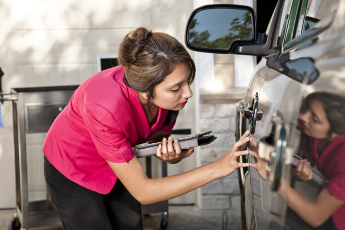 Automobile insurance adjuster inspecting damage to vehicle