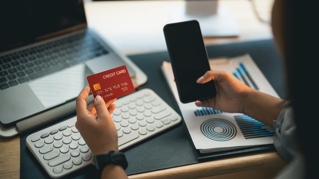 Close up Hand Woman holding credit card and using mobile to shopping online. asian woman working at home. Online shopping, e-commerce, internet banking, spending money, working from home concept.